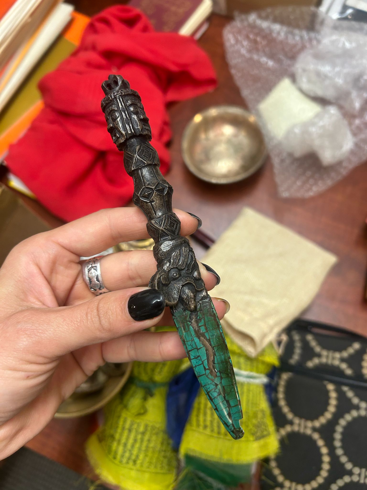 A hand holding a turquoise-inlaid phurba ritual dagger