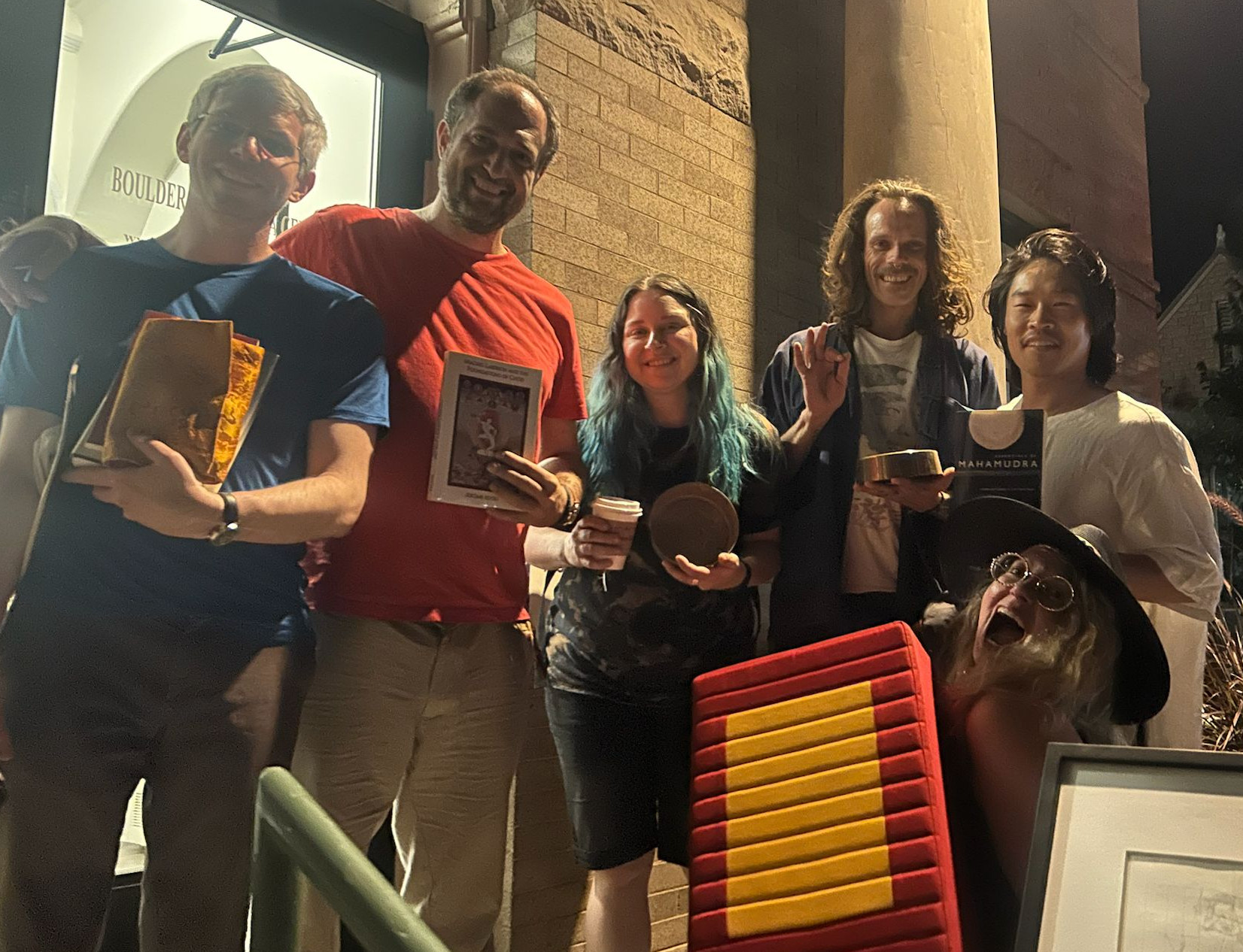 Happy practitioners outside in Boulder holding donated books, art, malas, and a meditation cushion