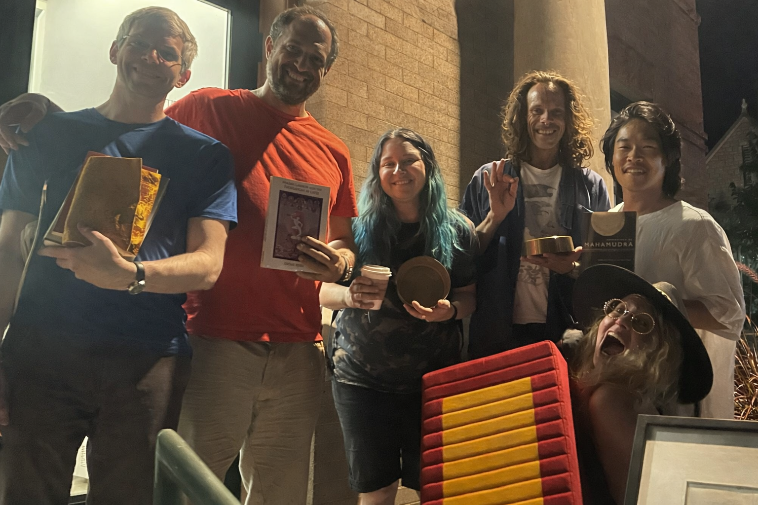 Happy practitioners outside in Boulder holding donated books, art, malas, and a meditation cushion